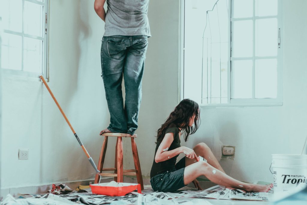 Two people painting a rental unit wall